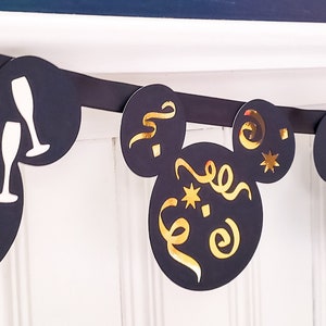 May include: Black and gold New Year's Eve party banner with Mickey Mouse ears and different designs, including a champagne bottle, a clock, and confetti.