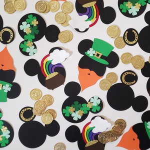 May include: A collection of black and green Mickey Mouse head cutouts with various St. Patrick's Day themed decorations, including shamrocks, rainbows, gold coins, and leprechaun hats.