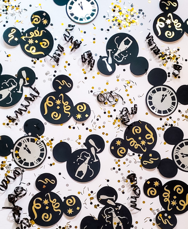 May include: Black and gold Mickey Mouse-shaped party decorations with a New Year's Eve theme. The decorations feature images of champagne bottles, clocks, and the text "Cheers" and "Happy New Year".