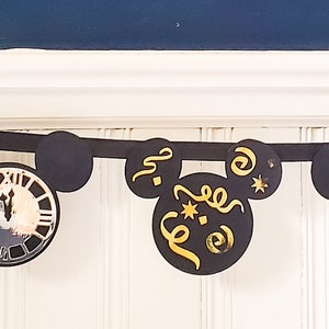 May include: Black and gold New Year's Eve party banner with Mickey Mouse ears and various celebratory designs, including champagne glasses, confetti, and a clock.