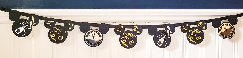 May include: Black and gold New Year's Eve party banner with Mickey Mouse ears and various celebratory designs, including champagne glasses, confetti, and a clock.