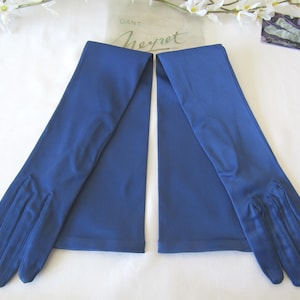 Peut inclure: Une paire de longs gants bleu roi. Les gants sont faits d'un tissu lisse et brillant et s'étendent bien au-delà du coude. Les gants sont posés sur une surface blanche. La marque "Heyret" est visible sur l'emballage.