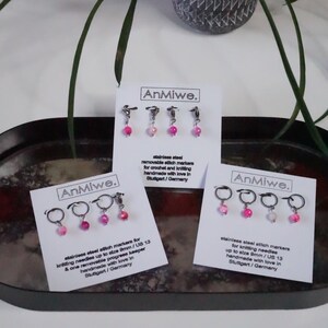 Puede incluir: Tres juegos de marcadores de punto AnMiwe para ganchillo y tejido. Cada juego presenta pequeños anillos de metal plateado con cuentas rosas y blancas. Las tarjetas dicen "marcadores de punto extraíbles de acero inoxidable".