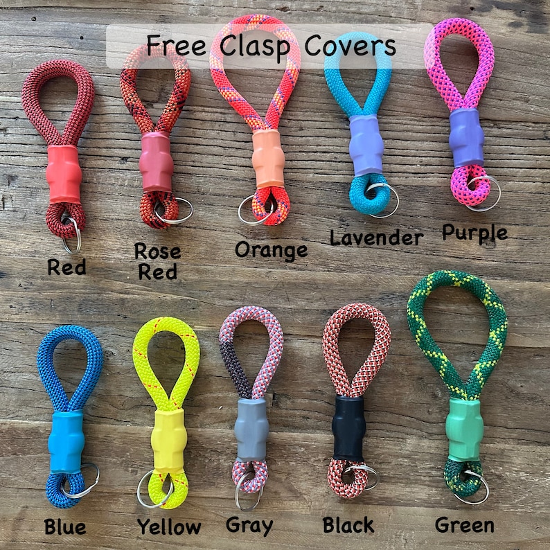 May include: Ten rope keychains with coloured clasp covers, labelled Red, Rose Red, Orange, Lavender, Purple, Blue, Yellow, Gray, Black, and Green. Each keychain features a braided loop, a solid-coloured plastic clasp cover, and a metal ring.