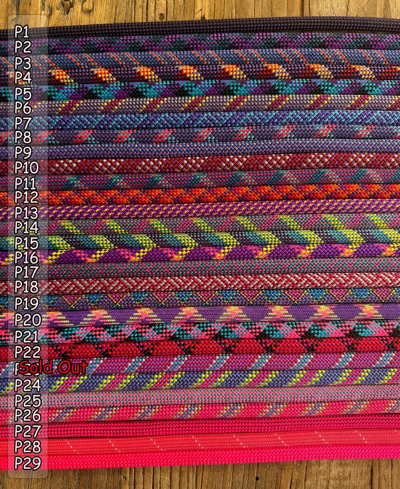 Puede incluir: Una colecci&oacute;n de veintinueve cordones trenzados dispuestos en filas paralelas, cada uno con distintas combinaciones de colores que incluyen morado, azul, naranja, verde, rojo y rosa, con etiquetas P1 a P29 y el texto Sold Out visible.
