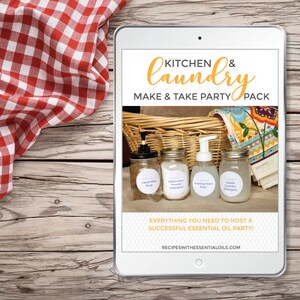 May include: A digital tablet displaying a graphic for a kitchen and laundry party pack. The graphic features a wicker basket with four glass jars filled with homemade cleaning products. The jars are labeled "Liquid Dish Soap", "Dishwasher Powder Detergent", "Foaming Hand Soap", and "Liquid Laundry Detergent". The text "KITCHEN & laundry MAKE & TAKE PARTY PACK" is displayed in a yellow font at the top of the graphic. The text "EVERYTHING YOU NEED TO HOST A SUCCESSFUL ESSENTIAL OIL PARTY!" is displayed in a yellow font at the bottom of the graphic. The text "RECIPESWITHESSENTIALOILS.COM" is displayed in a black font at the bottom of the graphic.