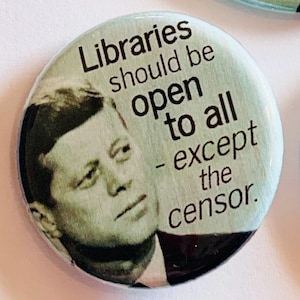 May include: A blue button with a black and white image of John F. Kennedy and the text "Libraries should be open to all - except the censor."
