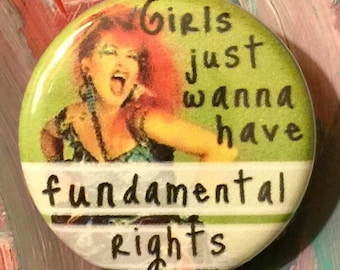 May include: A green button with a picture of a woman with red hair and the text "Girls just wanna have fundamental rights" in black.
