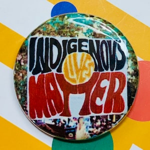 May include: A round button with a colorful design that says "Indigenous Lives Matter" in a retro font. The background is a collage of images.