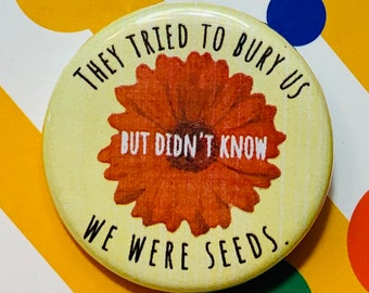 May include: A yellow button with a red flower and the text "They tried to bury us but didn't know we were seeds."