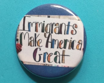 May include: A blue button with a white background and the text "Immigrants Make America Great" written in colorful letters.