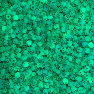 Peut inclure: Une image en gros plan d'une grande quantité de perles de crâne vertes qui brillent dans le noir. Les perles sont toutes de la même taille et de la même forme, et elles sont disposées de manière aléatoire.