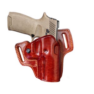 Peut inclure: Un étui en cuir marron avec une arme à feu beige à l'intérieur. L'étui a une boucle de ceinture et une fermeture à pression.