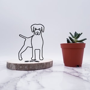 May include: Wire sculpture of a dog standing on a wooden base. The dog is black and the base is brown. A small potted succulent plant is in the background.