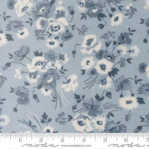 May include: Light blue floral fabric with a repeating pattern of white and blue flowers. The fabric features a variety of flower types, including roses and daisies, with green leaves and stems. The fabric is marked with a ruler in inches.