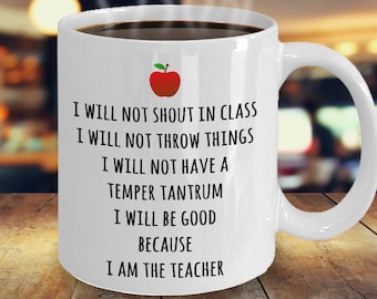 May include: White coffee mug with a red apple and black text that reads: "I will not shout in class. I will not throw things. I will not have a temper tantrum. I will be good because I am the teacher."