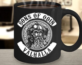 May include: Black ceramic coffee mug with a white graphic of a Viking warrior in a helmet with the text "Sons of Odin Valhalla" around the image.