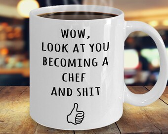 Könnte beinhalten: Weiße Keramik-Kaffeetasse mit schwarzem Text, der "WOW, LOOK AT YOU BECOMING A CHEF AND SHIT" lautet, mit einem Daumen-hoch-Emoji.