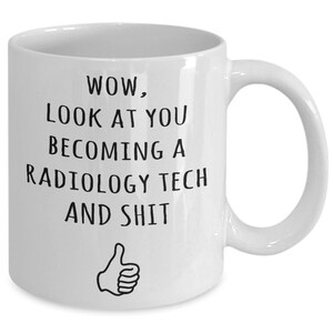 May include: White ceramic coffee mug with black text that reads "WOW, LOOK AT YOU BECOMING A RADIOLOGY TECH AND SHIT" with a thumbs up icon below the text.