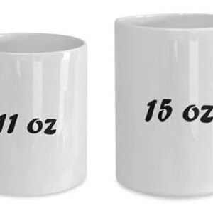 May include: Two white ceramic mugs. The mug on the left has "11 oz" printed on it, and the mug on the right has "15 oz" printed on it. Both mugs have a curved handle.