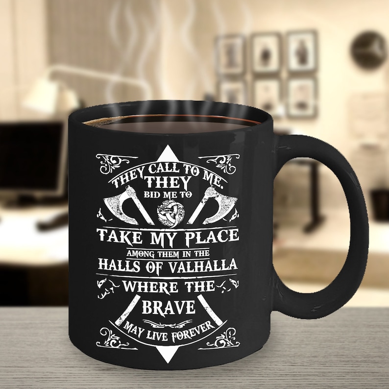 May include: Black coffee mug with white text that reads "They call to me. They bid me to take my place among them in the halls of Valhalla where the brave may live forever". The mug has a Viking symbol and two axes on it.