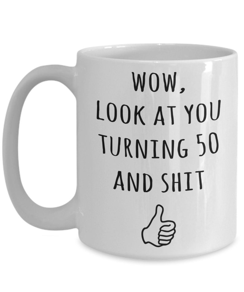 May include: White ceramic coffee mug with a black graphic that says "WOW, LOOK AT YOU TURNING 50 AND SHIT" with a thumbs up emoji.