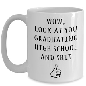 May include: White ceramic coffee mug with a black graphic that says "WOW, LOOK AT YOU GRADUATING HIGH SCHOOL AND SHIT" with a thumbs up emoji.