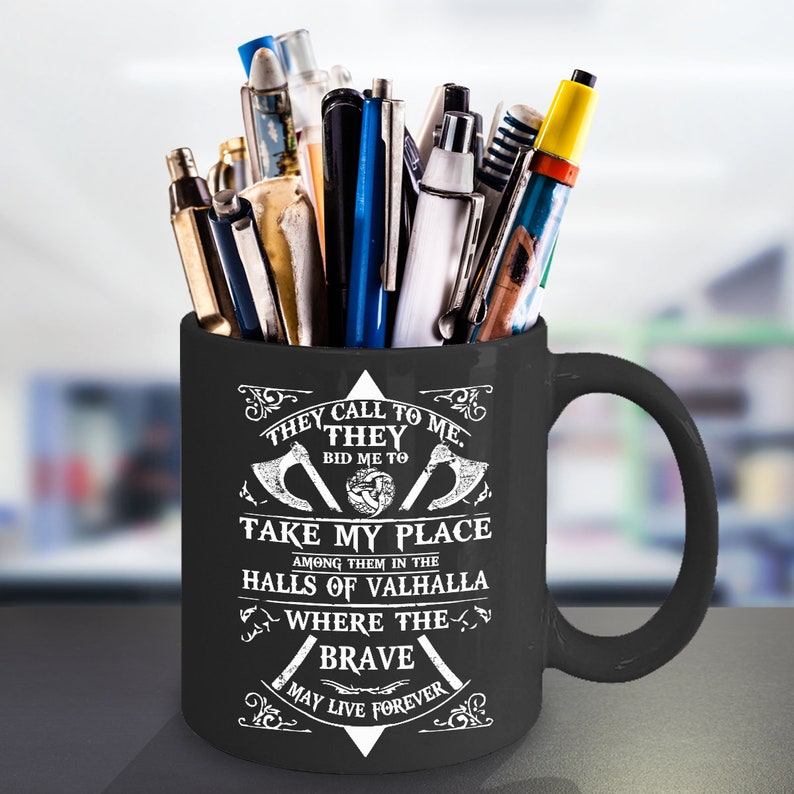 May include: Black coffee mug with a white design featuring a Viking symbol and the text "They call to me. They bid me to take my place among them in the halls of Valhalla where the brave may live forever."