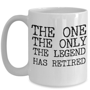 K&ouml;nnte beinhalten: Wei&szlig;e Keramik-Kaffeetasse mit schwarzem Text, der "The One The Only The Legend Has Retired" lautet.