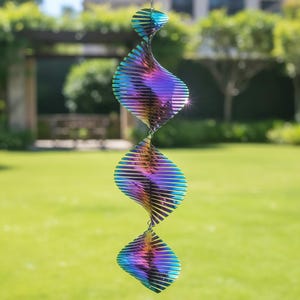May include: A hanging wind spinner with a mesmerizing iridescent finish. The decorative piece features a series of spiraling, diamond-shaped elements that reflect a spectrum of colors, including blues, purples, and greens. The wind spinner is suspended by a chain.