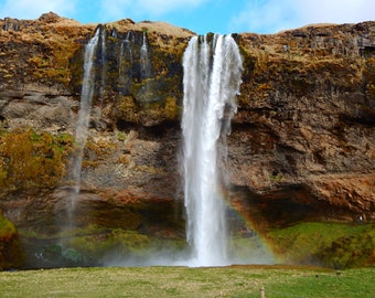 Könnte beinhalten: Ein großer Wasserfall stürzt von einer felsigen Klippe herab und erzeugt einen nebeligen Sprühnebel. Ein Regenbogen spannt sich über den Fuß des Wasserfalls und verleiht der Szene eine lebendige Note.