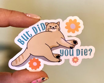 Può includere: Un adesivo bianco con un gatto dei cartoni animati che dice "Ma sei morto?" con uno sfondo blu e fiori arancioni.
