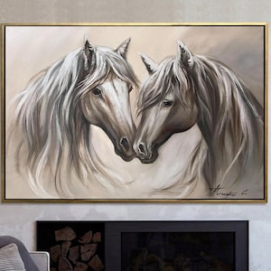 May include: An oil painting of two horses, heads touching, in shades of gray and white. The horses have long, flowing manes and are set against a neutral background. The artwork is framed in a gold-colored frame.