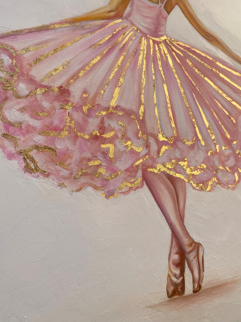 May include: A ballerina in a pink tutu with gold accents stands on her toes. The tutu is layered and has a ruffled bottom. The ballerina's legs are visible and she is wearing pointe shoes.