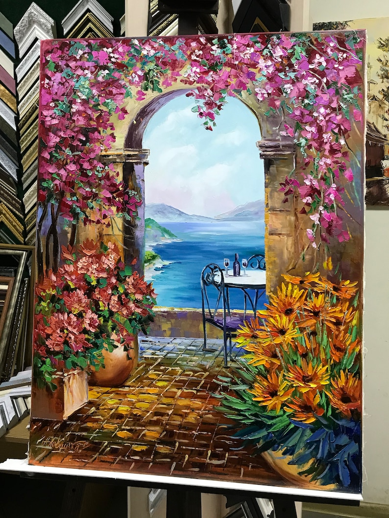 Puede incluir: Una pintura al &oacute;leo sobre lienzo que representa un arco de piedra con vistas a un mar azul. La escena muestra vibrantes buganvillas rosas colgando del arco, macetas de terracota con flores naranjas y rojas, y una mesa con dos copas.