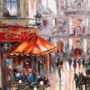 May include: A painting of a street scene with an orange umbrella over a cafe table. The cafe is located in a European city with tall buildings and a cobblestone street. The painting is done in a painterly style with loose brushstrokes and vibrant colors.