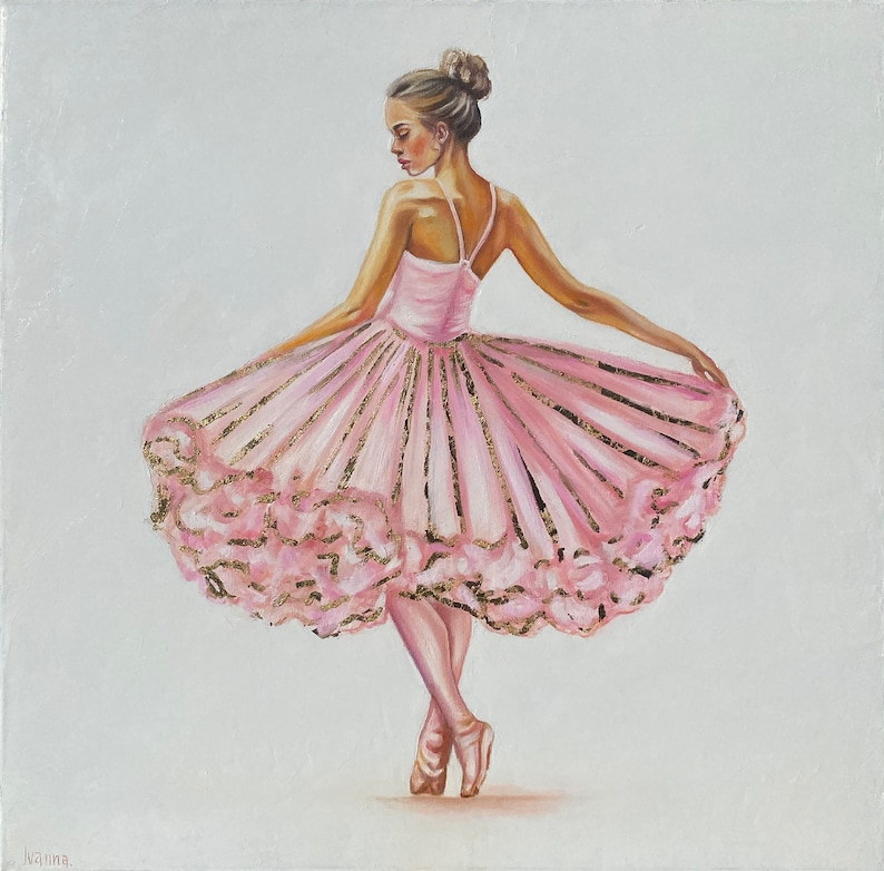 May include: A ballerina in a pink tutu with gold accents stands on one leg, her other leg extended behind her. The tutu is layered and has a ruffled edge. The ballerina is wearing pointe shoes.