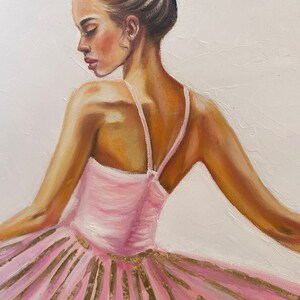 May include: A painting of a ballerina wearing a pink tutu with gold accents. The ballerina is facing away from the viewer and has her hair pulled back in a bun.
