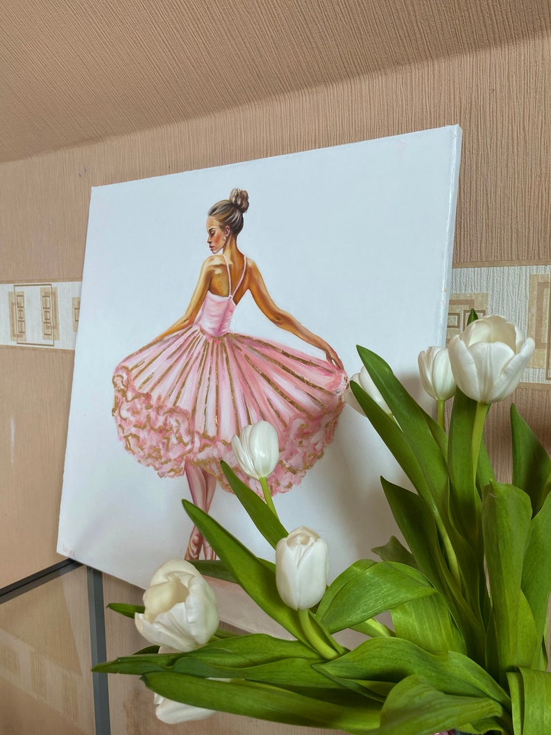 May include: A painting of a ballerina wearing a pink tutu with gold accents. The ballerina is standing on one leg with her other leg extended behind her. The background is white.