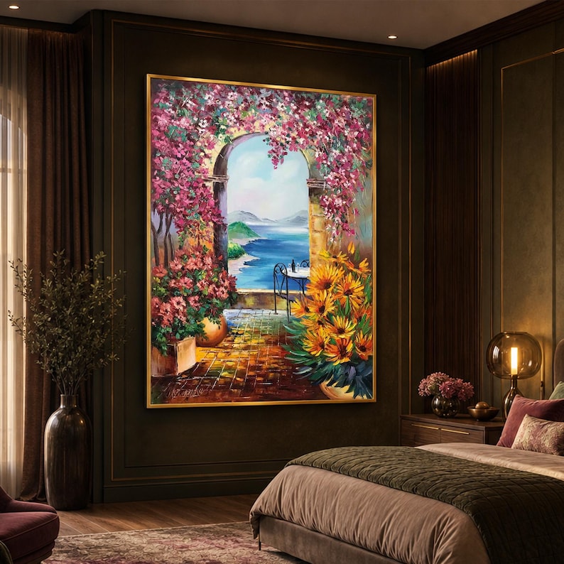 Puede incluir: Una pintura al &oacute;leo rectangular en un marco dorado que representa una escena de terraza mediterr&aacute;nea. La vista a trav&eacute;s de un arco de piedra muestra un mar azul y colinas distantes. Flores de buganvilla rosa cubren el arco, con flores amarillas.