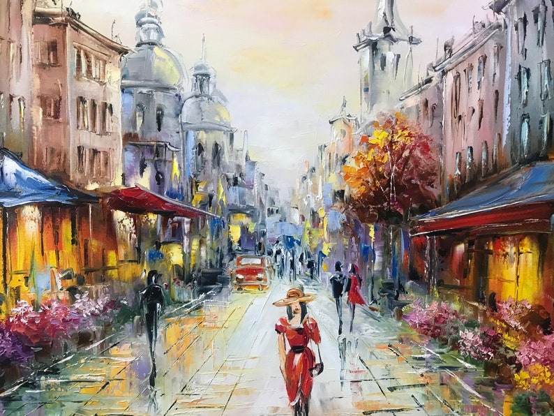 May include: Oil painting of a European city street scene. A woman in a red dress and hat walks toward the viewer. Buildings line the street, and a red car is visible. The artwork uses a palette of blues, yellows, and reds.