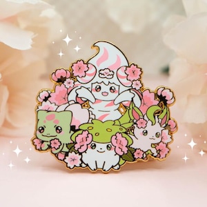 May include: A gold-toned metal enamel pin featuring four stylized cartoon creatures surrounded by pink cherry blossom flowers. The design includes a central cream-colored figure, a green creature on the left, a white creature at the bottom, and a light pink creature on the right.