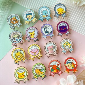 May include: A set of 15 enamel pins featuring various Pokemon characters with humorous phrases. The pins are gold-colored and have a ribbon design. The phrases include "Always Tired", "Did the Thing", "Corporate Slave", "Crybaby", "Anxious", "Introvert", "Dead Inside", "Overthinker", "Still Alive", "Procrastinator", "Healing", "One Brain Cell", "Don't Give a Flying Fuck", "Full of Rage", and "Fuck".