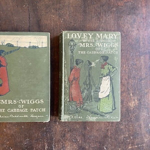Peut inclure: Deux livres anciens reliés en vert avec des illustrations et du texte. Le livre de gauche est intitulé "Mrs. Wiggs of the Cabbage Patch" par "Alice Caldwell Hegan". Le livre de droite est intitulé "Lovey Mary" par "Alice Hegan Rice".