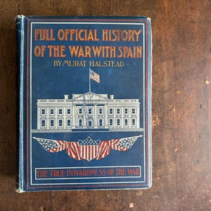 May include: A vintage book titled "FULL OFFICIAL HISTORY OF THE WAR WITH SPAIN" by Murat Halstead. The cover is blue with a white illustration of a building, an American flag, and red and white banners.