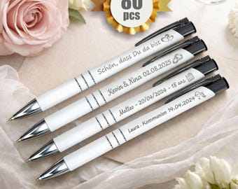 Op de afbeelding: Vier witte pennen met zwarte accenten en zilveren punten worden getoond. Elke pen heeft aangepaste tekst, inclusief namen en data. Een gouden embleem met "80 stuks" staat op de achtergrond. De pennen zijn gerangschikt op een zacht, lichtgekleurd oppervlak met bloemaccenten.