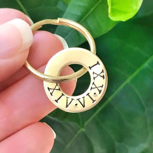 Peut inclure: Porte-clés en métal doré avec un charme rond orné de chiffres romains de I à XII.