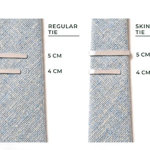 May include: Two light blue ties with silver tie bars. The text "REGULAR TIE" and "SKINNY TIE" are above the ties. Measurements are provided in centimeters: 5 cm and 4 cm.
