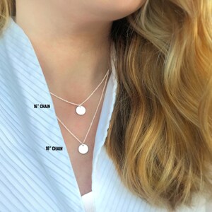 May include: Two silver necklaces with round pendants. The top necklace is 16 inches long and the bottom necklace is 18 inches long.