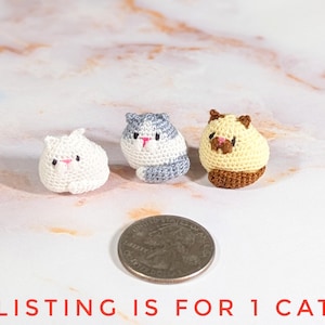 May include: Three small, crocheted cat figurines in white, gray and white, and cream colors. The cats have pink noses and black eyes. A quarter is next to the cats for size comparison. The text at the bottom says "LISTING IS FOR 1 CAT".